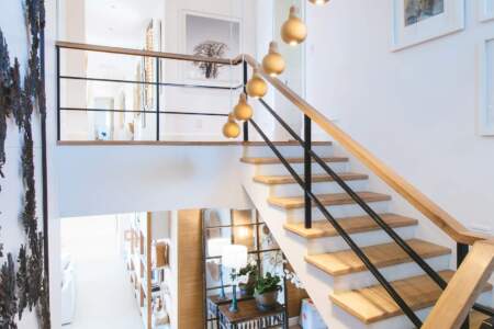 Offene Treppe mit Holzstufen und Designer-Lampen in einem hell eingerichteten Innenraum.